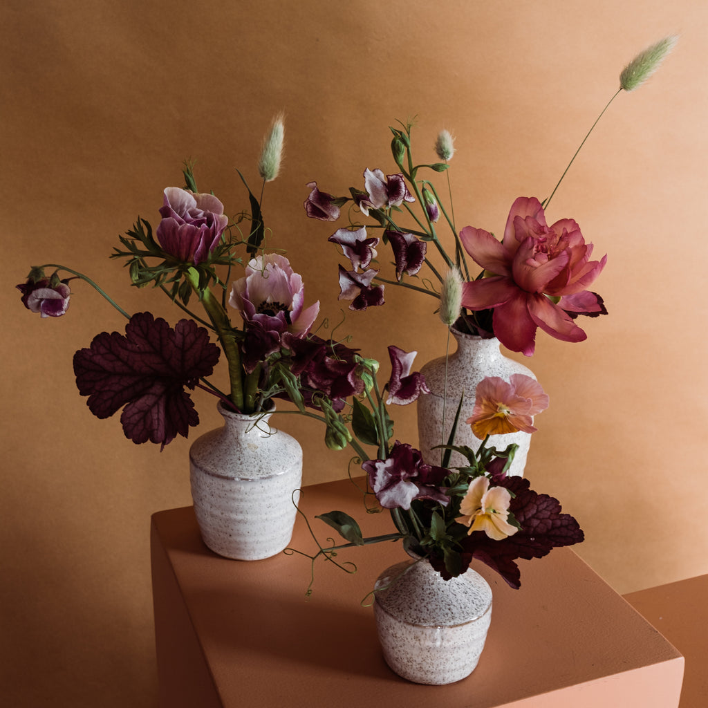 Three bud vase arrangements with seasonal flowers in ceramic vessels designed in Toronto